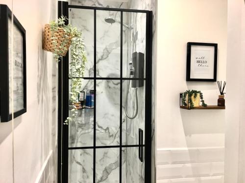 ホーイックにあるCozy and modern flat in the heart of Hawickの大理石の壁の客室で、ガラス張りのシャワードアが付いています。