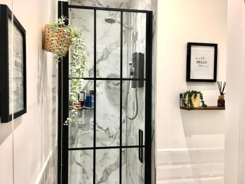 a glass shower door in a room with a marble wall at Cozy and modern flat in the heart of Hawick in Hawick