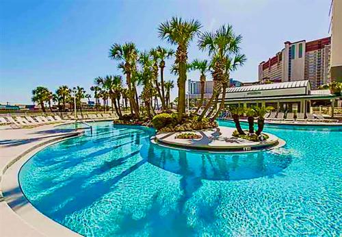 a large blue pool with palm trees in a resort at Emerald Bay Escape in Panama City Beach