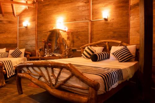 Dudley Nature Resort في هارابانا: غرفة نوم بسريرين في غرفة بجدران خشبية