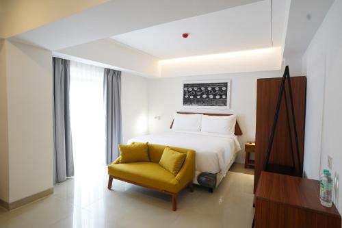 a bedroom with a bed and a yellow chair at Coffee Hotel Ayola Dolok Sanggul in Sigumpar