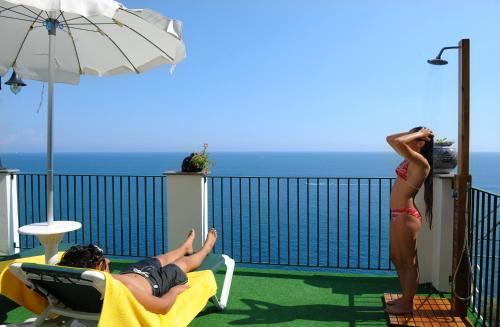 two women laying in chairs on a balcony with the ocean at Hotel Villa Maria Pia in Praiano