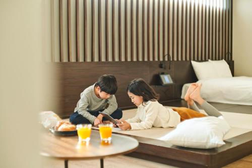 FAV HOTEL TAKAMATSU في تاكاماتسو: رجل وامرأة يجلسون على الأرض في غرفة فندق