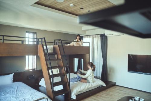 高松的住宿－FAV HOTEL TAKAMATSU，两个女孩坐在卧室的双层床上