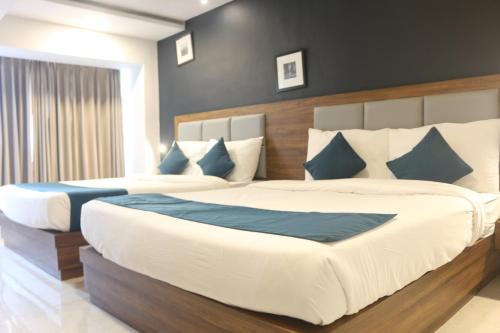 a bedroom with two beds with blue and white pillows at Hotel Palm Beach Pride in Mumbai