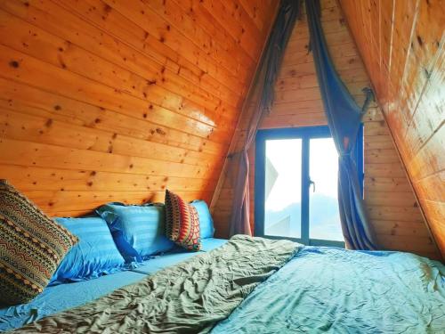 a bed in a log cabin with a window at Sa Mộc House Tam Đảo - Venuestay in Vĩnh Phúc
