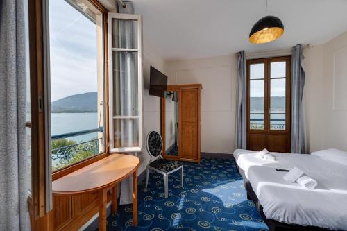 a hotel room with two beds and a window at Le Pavillon des Fleurs in Menthon-Saint-Bernard