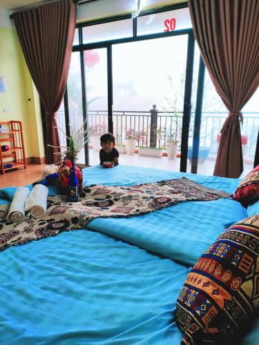 a little boy sitting on a large blue bed at Sa Mộc House Tam Đảo - Venuestay in Vĩnh Phúc