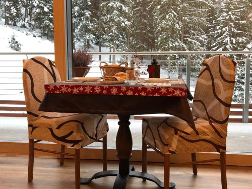 einen Tisch und zwei Stühle mit Tisch und Schnee in der Unterkunft B&B Le Stagioni di Stava in Tesero