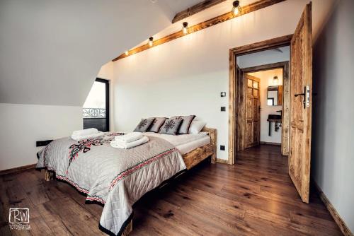ein Schlafzimmer mit einem großen Bett und Holzboden in der Unterkunft Laura Resort - Luxury Chalets z jacuzzi in Szaflary