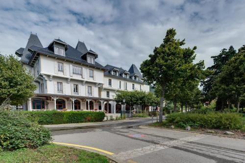 a large white building with a black roof on a street at Le Pavillon des Fleurs in Menthon-Saint-Bernard