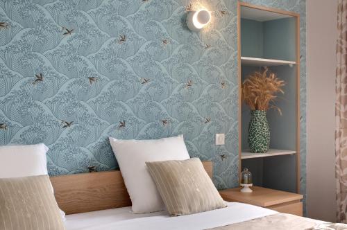 a bedroom with blue wallpaper with a bed with a pillow at Hôtel de France in Montmarault