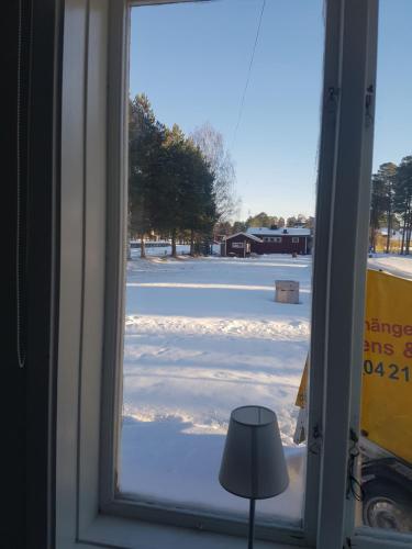 a window with a view of a snow covered parking lot at Furudals Vandrarhem och Sjöcamping in Furudal