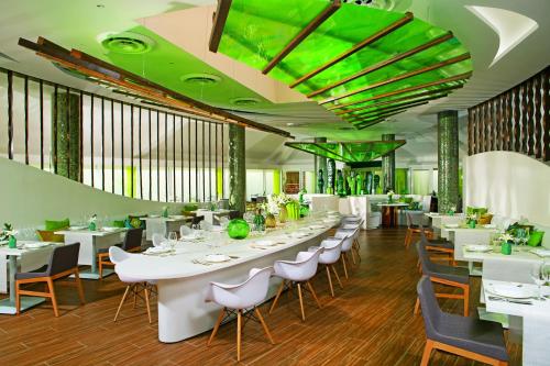 a restaurant with white tables and chairs and green ceilings at Breathless Punta Cana Resort & Spa - Adults Only in Punta Cana