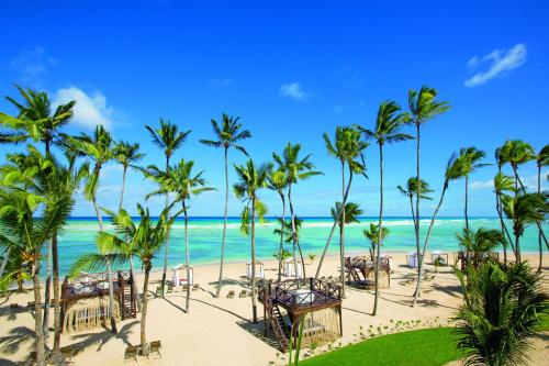 een strand met palmbomen en tafels en de oceaan bij Breathless Punta Cana Resort & Spa - Adults Only - All Inclusive in Punta Cana