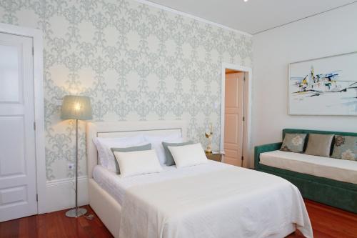 um quarto com uma cama branca e um sofá verde em Charming House Marquês no Porto