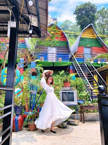a woman in a white dress standing in front of a mural at Sa Mộc House Tam Đảo - Venuestay in Vĩnh Phúc