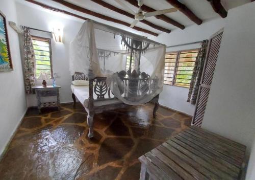 a room with a bed and a table and windows at Marine Holiday House in Malindi
