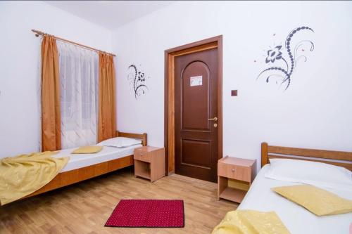 a room with two beds and a wooden door at Pensiunea Sabrina in Lacu Sărat