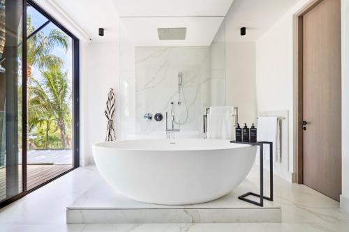 une grande baignoire blanche dans une salle de bain avec une fenêtre dans l'établissement LUX* Grand Baie Resort & Residences, à Grand Baie