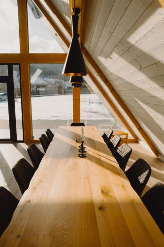 a long wooden table with chairs and a lamp at Treeline Cabins in Cădăreşti