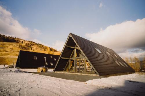 a large black barn with a large window at Treeline Cabins in Cădăreşti