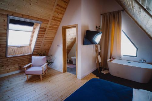 a bathroom with a tub and a chair and a tv at Treeline Cabins in Cădăreşti