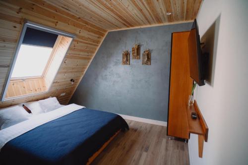 a small bedroom with a bed and a window at Treeline Cabins in Cădăreşti