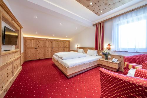 sypialnia z łóżkiem i czerwonym dywanem w obiekcie Hotel Similaun w mieście Vent