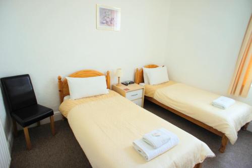 two twin beds in a room with a chair at Morrisy House in Blackpool