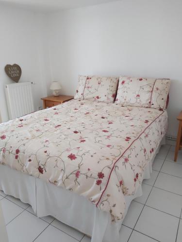 - un lit avec un couvre-lit blanc et des fleurs dans l'établissement Chez Turnbulls, à Pomport