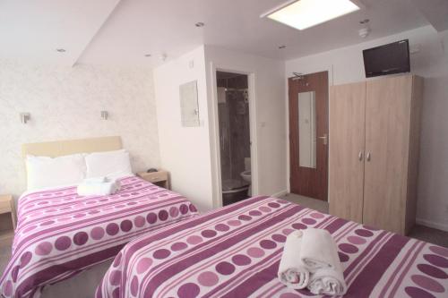 a bedroom with two beds with purple and white sheets at Morrisy House in Blackpool