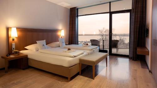 a bedroom with a large bed and a large window at Parkhotel St.Leonhard in Überlingen