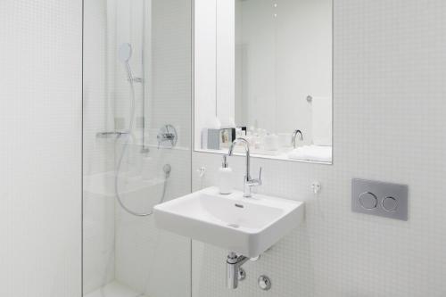 a white bathroom with a sink and a shower at Boutique Hotel Helvetia in Zurich