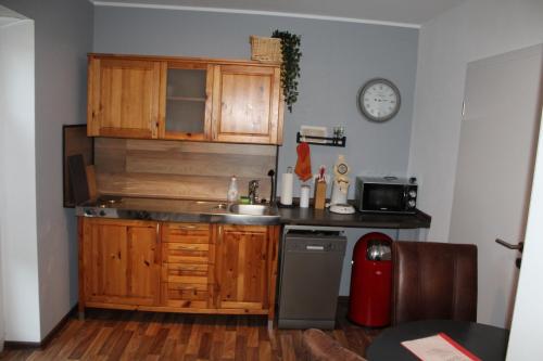 a kitchen with wooden cabinets and a sink and a clock at Appartement Luna in Ruppach-Goldhausen