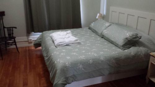 a bed with a green comforter and two towels on it at Centralia Square Grand Ballroom and Vintage Hotel in Centralia