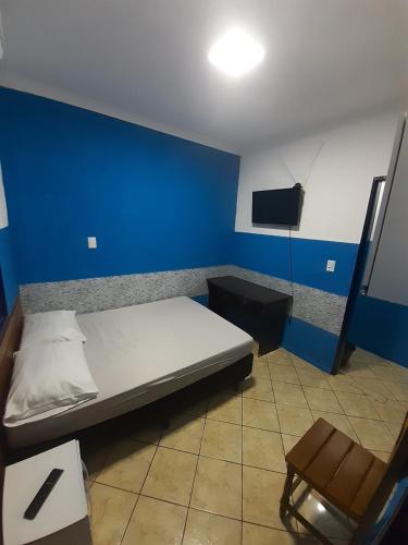 Schlafzimmer mit einem Bett, einem TV und einem Stuhl in der Unterkunft Melhor Custo x benefício - Tompell Pousada Bem-te-vi - Portaria só até 22 horas in Ponta Porã