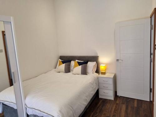 a bedroom with a white bed and a night stand with a lamp at Modern and spacious two bedroom apartment in Ipswich