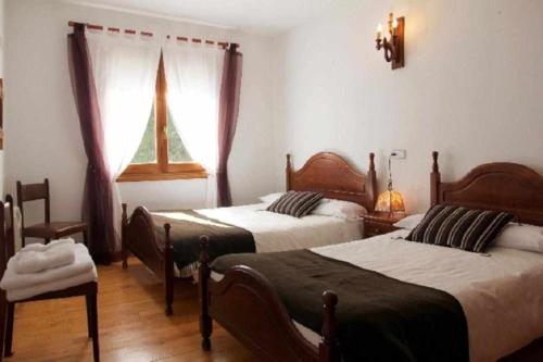 Un dormitorio con dos camas y una ventana. en Casa Rural Mantxoalorra, en Ochagavía