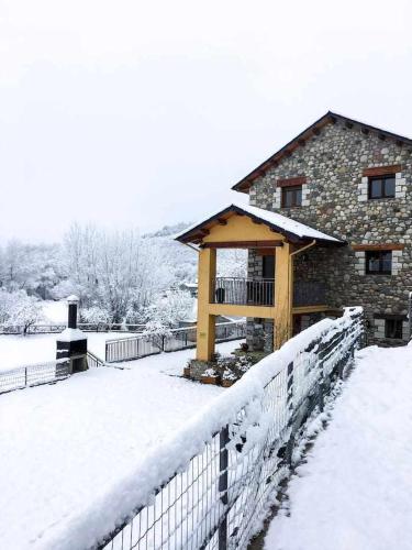 a building with a fence in the snow at El Jardí Casa rural ideal para familias y grupos in Arfa