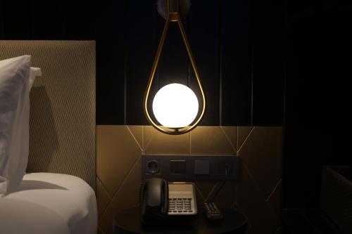a lamp with a phone on a table next to a bed at Awann Sewu Boutique Hotel and Suite Semarang in Semarang