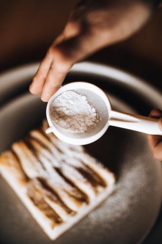 a person holding a cup of coffee next to a plate with two utensils at freiraum Apartments in Mellau