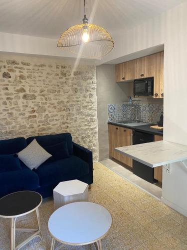 un soggiorno con divano blu e una cucina di La tour 2: Appart neuf au cœur de la petite venise a LʼIsle-sur-la-Sorgue