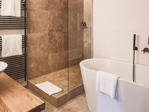 a bathroom with a tub and a glass shower at Das Achental Resort in Grassau