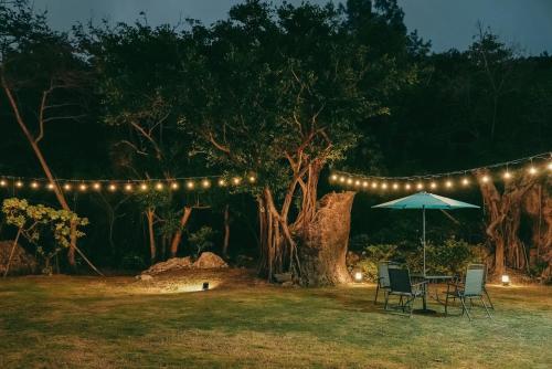 Un patio con mesa, sillas y luces. en Linwu 05 墾丁包棟民宿, en Eluan