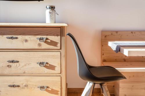 a black chair sitting next to a wooden dresser at Brugghof Apartement Lärche in San Felice
