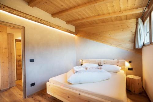 a bedroom with a white bed with a wooden ceiling at Brugghof Apartement Lärche in San Felice