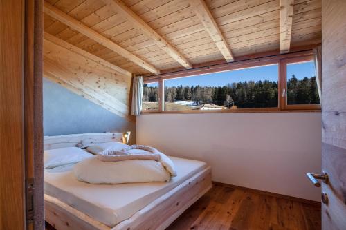 una camera da letto in una casetta minuscola con una grande finestra di Brugghof Apartement Lärche a San Felice