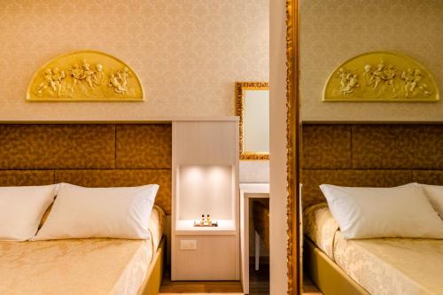 a bedroom with two beds and a mirror at Hotel Mazzanti in Milano Marittima