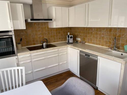 a kitchen with white cabinets and a sink and a dishwasher at Kleines, gemütliches Haus in Bonn in Bonn